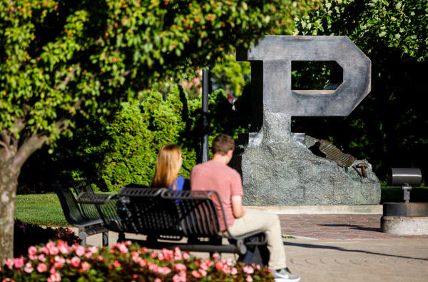 people on bench next to Purdue P statue in summer